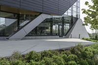 an empty courtyard near some plants and trees with large windows on top of the building