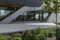 an empty courtyard near some plants and trees with large windows on top of the building