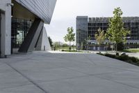 a large concrete sidewalk leading to two modern buildings in the background with a green lawn on each side