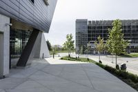 a large concrete sidewalk leading to two modern buildings in the background with a green lawn on each side