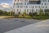 a city street surrounded by grass and tall buildings at the end of a street there is a paved pathway in front of the building