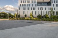 a city street surrounded by grass and tall buildings at the end of a street there is a paved pathway in front of the building