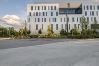 a city street surrounded by grass and tall buildings at the end of a street there is a paved pathway in front of the building