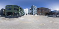 a fisheye image of a very large building in the middle of a street with a parking lot on one side and cars on the other side