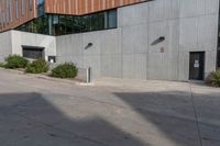 a red fire hydrant is on the pavement in front of a large grey building