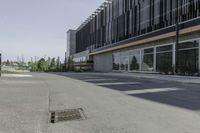 a manhole drain on the side of a street leading to a large building with multiple windows