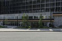 a street view from an intersection looking at a building and buildings behind it with glass windows