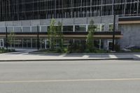 a street view from an intersection looking at a building and buildings behind it with glass windows