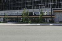 a street view from an intersection looking at a building and buildings behind it with glass windows