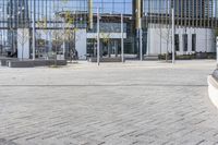 an empty square with glass walls in the background of it and a bus parked in front