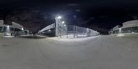 the view from a fish eye lens into a baseball stadium at night, with a person on a skateboard in the foreground