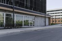 a road next to an office building with glass doors and windows on both sides of it