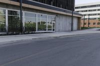 a road next to an office building with glass doors and windows on both sides of it