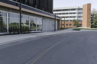 a road next to an office building with glass doors and windows on both sides of it