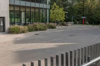 the view of an open air parking lot near a tall building with windows and a fence