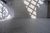 a wall and floor in a large building under sunlight filters and shadows, with a shadow cast on it