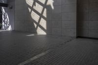 a wall and floor in a large building under sunlight filters and shadows, with a shadow cast on it