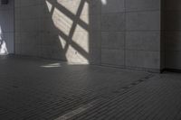a wall and floor in a large building under sunlight filters and shadows, with a shadow cast on it