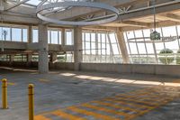 a empty parking garage with large windows and yellow markings on it's floor, as well as a clock