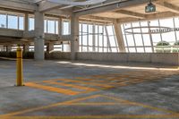 a empty parking garage with large windows and yellow markings on it's floor, as well as a clock