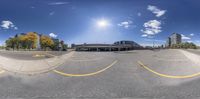 a fish eye view of a parking lot with a lot to the side and buildings in the background