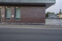 a red stop sign sitting on the side of a road next to a red brick building