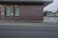 a red stop sign sitting on the side of a road next to a red brick building