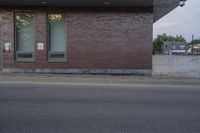 a red stop sign sitting on the side of a road next to a red brick building