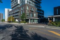 tall residential building next to sidewalk with trees in front of it and blue skies above