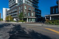 tall residential building next to sidewalk with trees in front of it and blue skies above