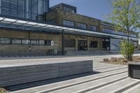 two wooden benches are in front of a large building with windows on the side and skylights above them