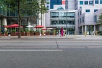 people walk in front of some office buildings while others walk by on the sidewalk and street