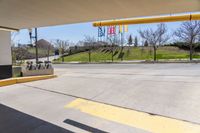 the yellow lines on the road is near the gas station and park signs in the background