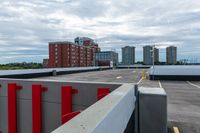 a large parking lot with a tall building in the background and a row of parked cars