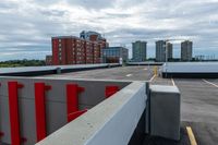 a large parking lot with a tall building in the background and a row of parked cars