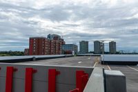 a large parking lot with a tall building in the background and a row of parked cars