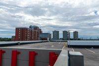 a large parking lot with a tall building in the background and a row of parked cars