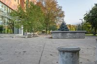 a white garbage can sitting on top of a cement floor next to a building near trees