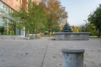 a white garbage can sitting on top of a cement floor next to a building near trees