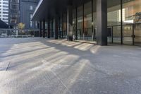 a building with large windows next to a sidewalk with parking meters in front of it