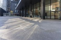 a building with large windows next to a sidewalk with parking meters in front of it