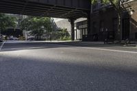 a street with several parked cars and buildings on it in the distance is an empty sidewalk with a fence at one end