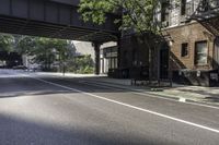 a street with several parked cars and buildings on it in the distance is an empty sidewalk with a fence at one end