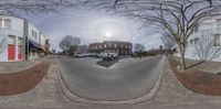 a 360 - view photo of a street with cars on the road near buildings in a neighborhood