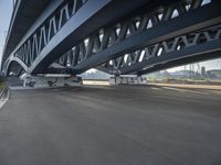 a bike sits underneath an empty, pedestrian bridge during daytime time in a city setting