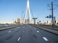 a large bridge that crosses the street in the city with high rise traffic and a crosswalk