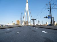 a large bridge that crosses the street in the city with high rise traffic and a crosswalk