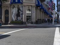 people are walking down the road near a store with blue and white awnings