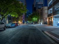 a city street at night with parking meters on either side and the road in the center