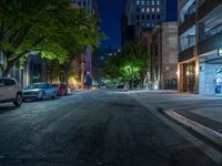 a city street at night with parking meters on either side and the road in the center